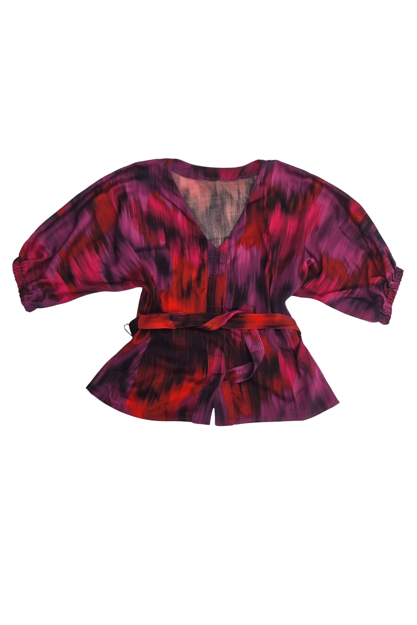 Eine luxuriöse, adaptive Bluse aus 100% Viskose-Satin in leuchtenden Fuchsia-, Rot- und Lilatönen, mit Fledermausärmeln und einem passenden Gürtel. Die Bluse ist speziell mit drei Magnetverschlüssen ausgestattet, was sie ideal für Menschen mit Tetraplegie oder eingeschränkter Handfunktion macht.