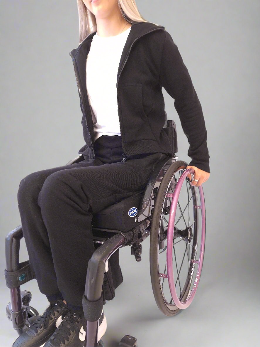 Girl in a wheelchair dressed in Vilber's woman's jersey wheelchair adaptive pants and black jacket