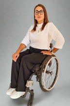 Woman in a wheelchair wearing Vilber's adaptive office clothing - white blouse and black pants