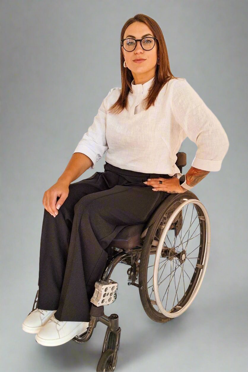 Woman in a wheelchair wearing Vilber's adaptive office clothing - white blouse and black pants